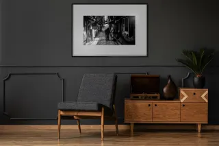 Dans un salon aux murs sombres, un cadre encadre une photographie en noir et blanc d'une ruelle ; rien ne distingue l'&eacute;cran &agrave; encre &eacute;lectronique d'un tirage sous verre