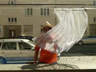 Un passant coiff&eacute; d'un chapeau de paille s'arr&ecirc;te devant une vitrine ; un petit rideau de dentelle s'est d&eacute;plac&eacute; sur la tringle et lui masque le visage