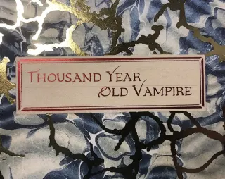 La couverture du livre : une &eacute;tiquette de papier coll&eacute;e sur un papier marbr&eacute; bleu et or, o&ugrave; le titre est calligraphi&eacute; en rouge.
